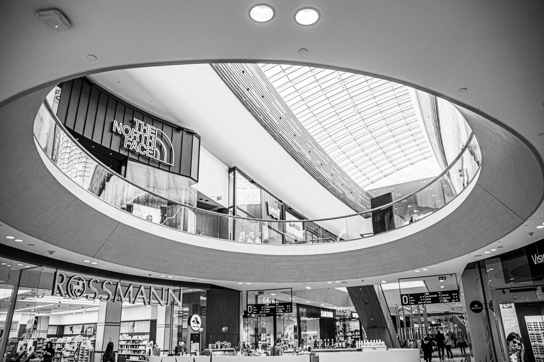 Black and white image showcasing the modern interior design of a shopping mall with prominent brand displays.