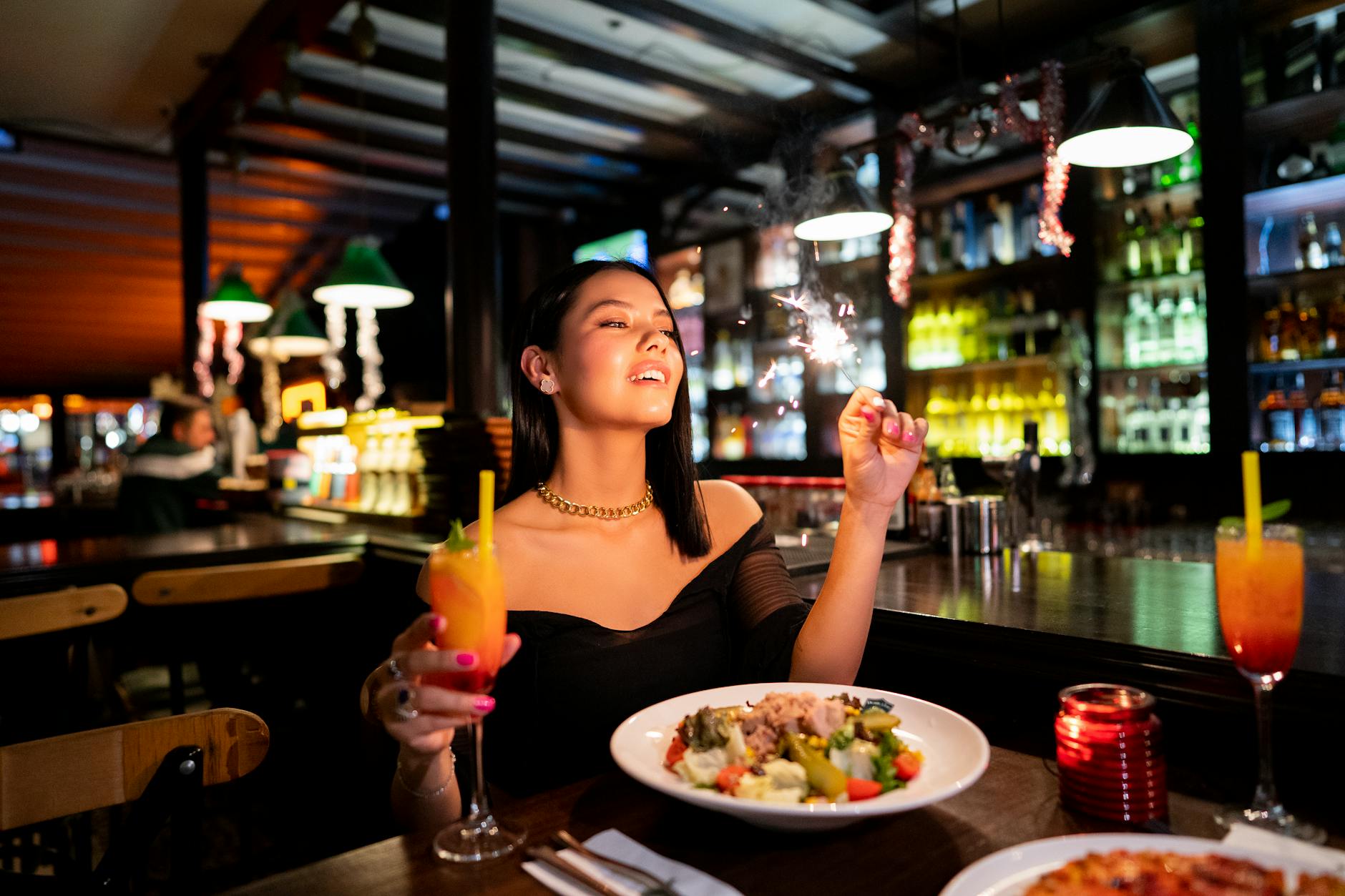 A woman savoring a cocktail and meal in a vibrant Istanbul bar, exuding a sense of leisure.