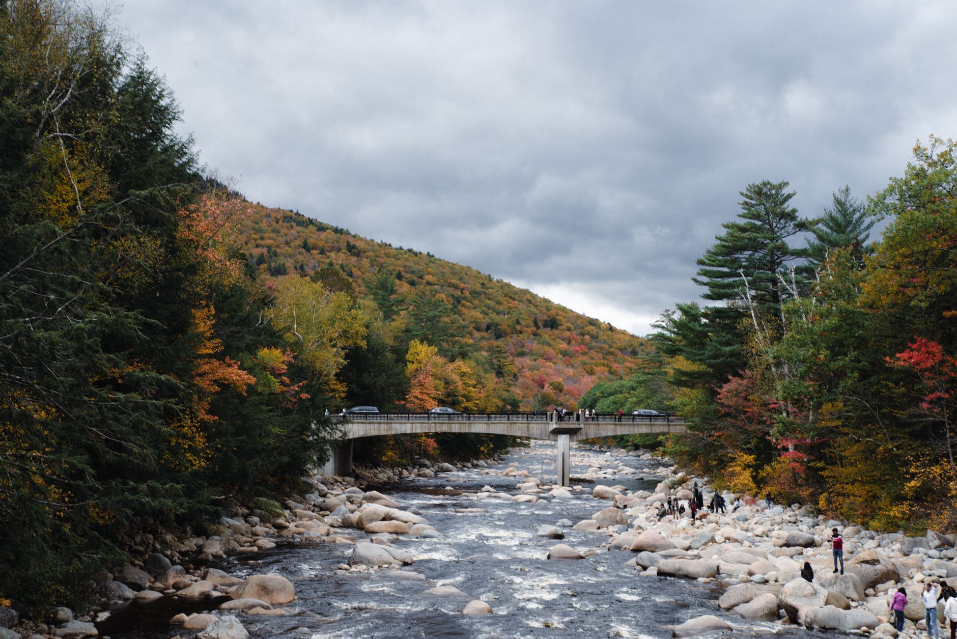 Picturesque autumn landscape with a bridge, forest, and river, perfect for fall travel themes.