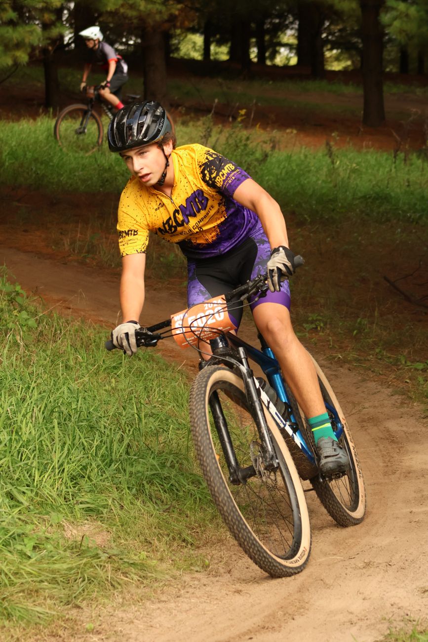 Teenager riding mountain bike on forest trail during race event.