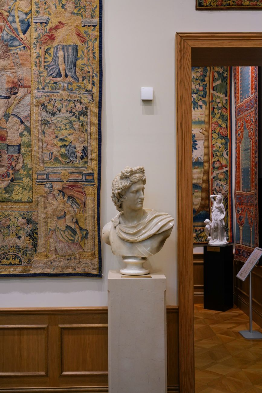 Elegant art museum interior featuring classical sculpture and ornate tapestries.