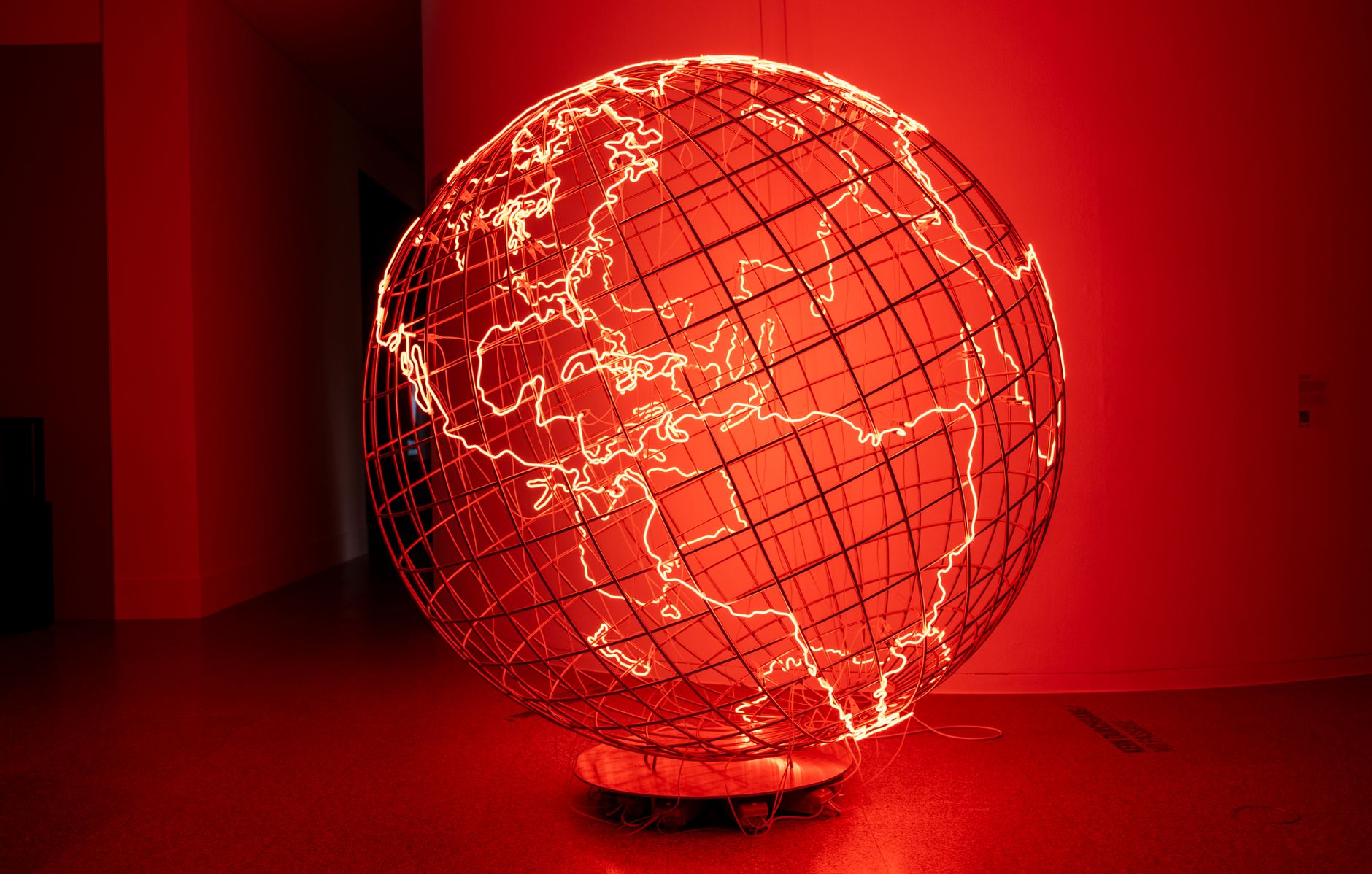 A striking illuminated globe sculpture displayed in a dimly lit art exhibition in Bonn, Germany.
