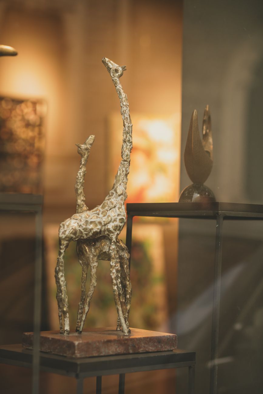 Close-up of an artistic bronze giraffe sculpture in a museum exhibit.