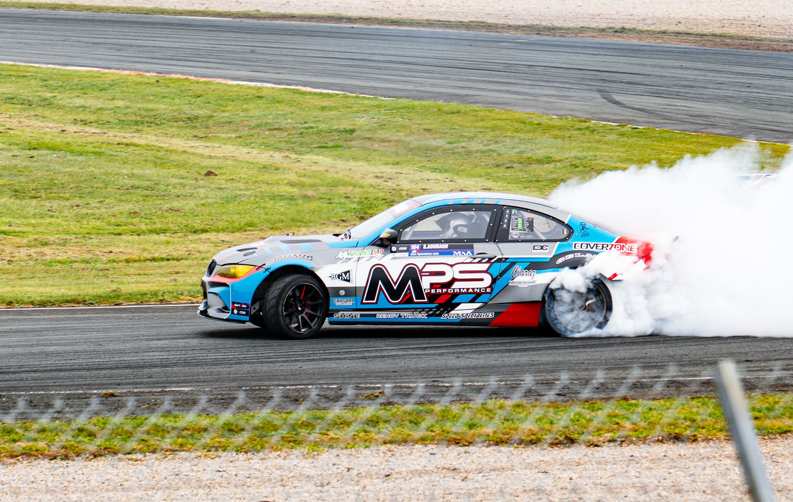 Stock cars racing on a vibrant day at Phoenix International Raceway with a large audience.
